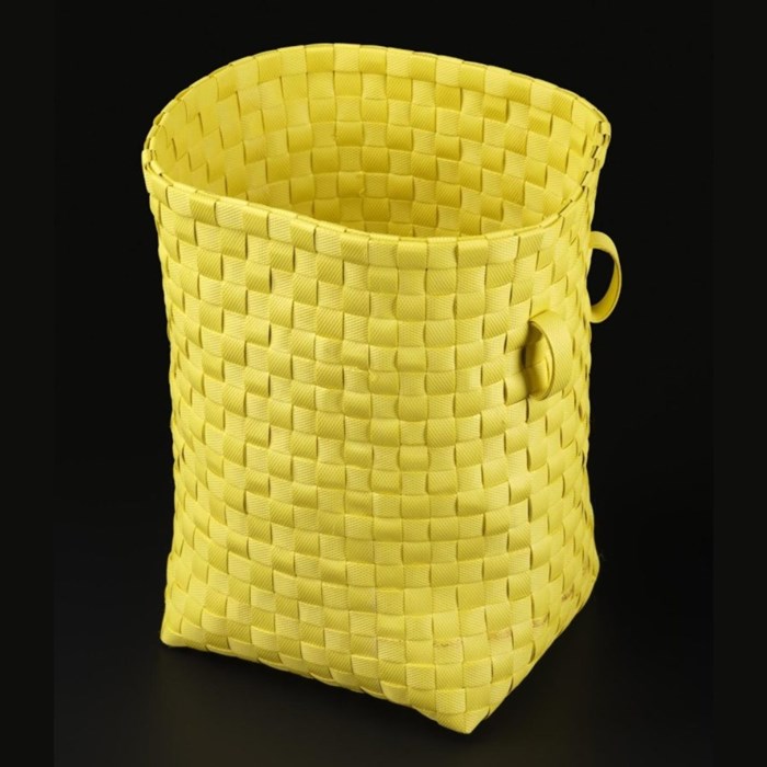 A tall, rectangular woven basket with open top against a black background. The basket is bright yellow and woven with thick strands of discarded plastic which form a textured pattern of squares. It has two small handles on the right.