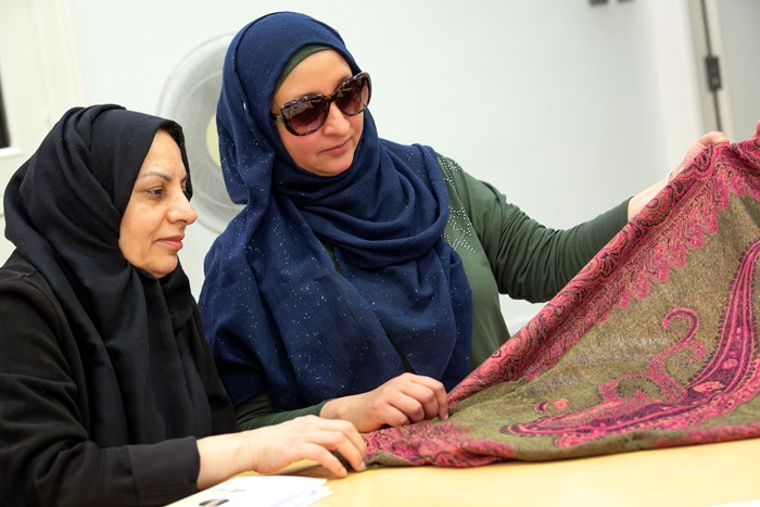 Two people hold Paisley shawl together during a group discussion.