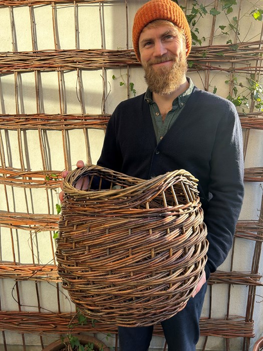 Man standing holding willow basket