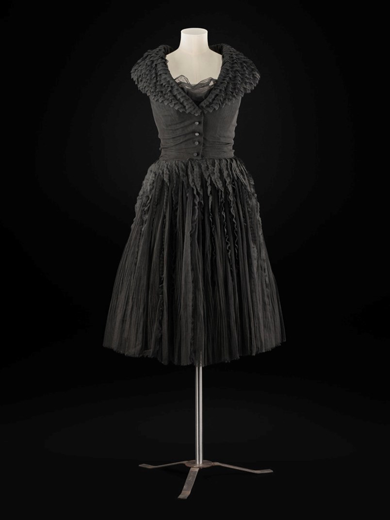  Woman’s dress, of black tulle and lace, sleeveless, deep v-shaped neckline, wide shawl collar.