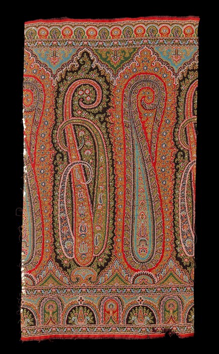 Paisley shawl pattern, short length of a woven border with long cone or buta shapes at the centre, detailed multi-coloured design predominantly in shades of red, blue and green.