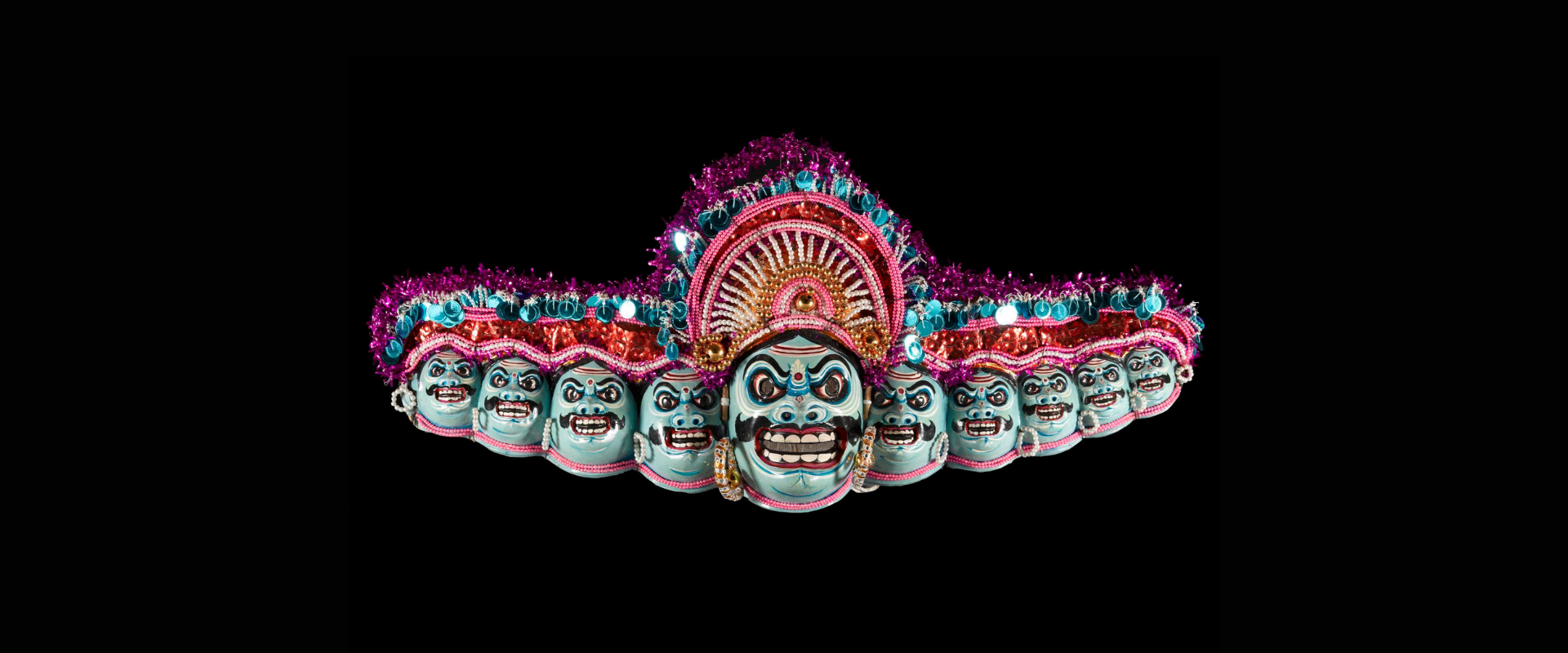 Ten headed papier-mache mask of the demon king Ravana, part of a Chhou dance costume, painted in blues, red, white and black and decorated with beads, sequins and tinsel: India, Bengal, Purulia District, by Nepal Chandra Sutradhar.