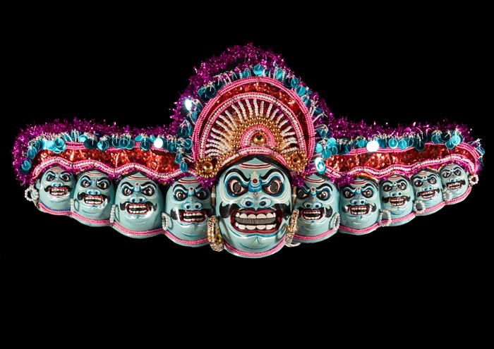 Ten headed papier-mache mask of the demon king Ravana, part of a Chhou dance costume, painted in blues, red, white and black and decorated with beads, sequins and tinsel.