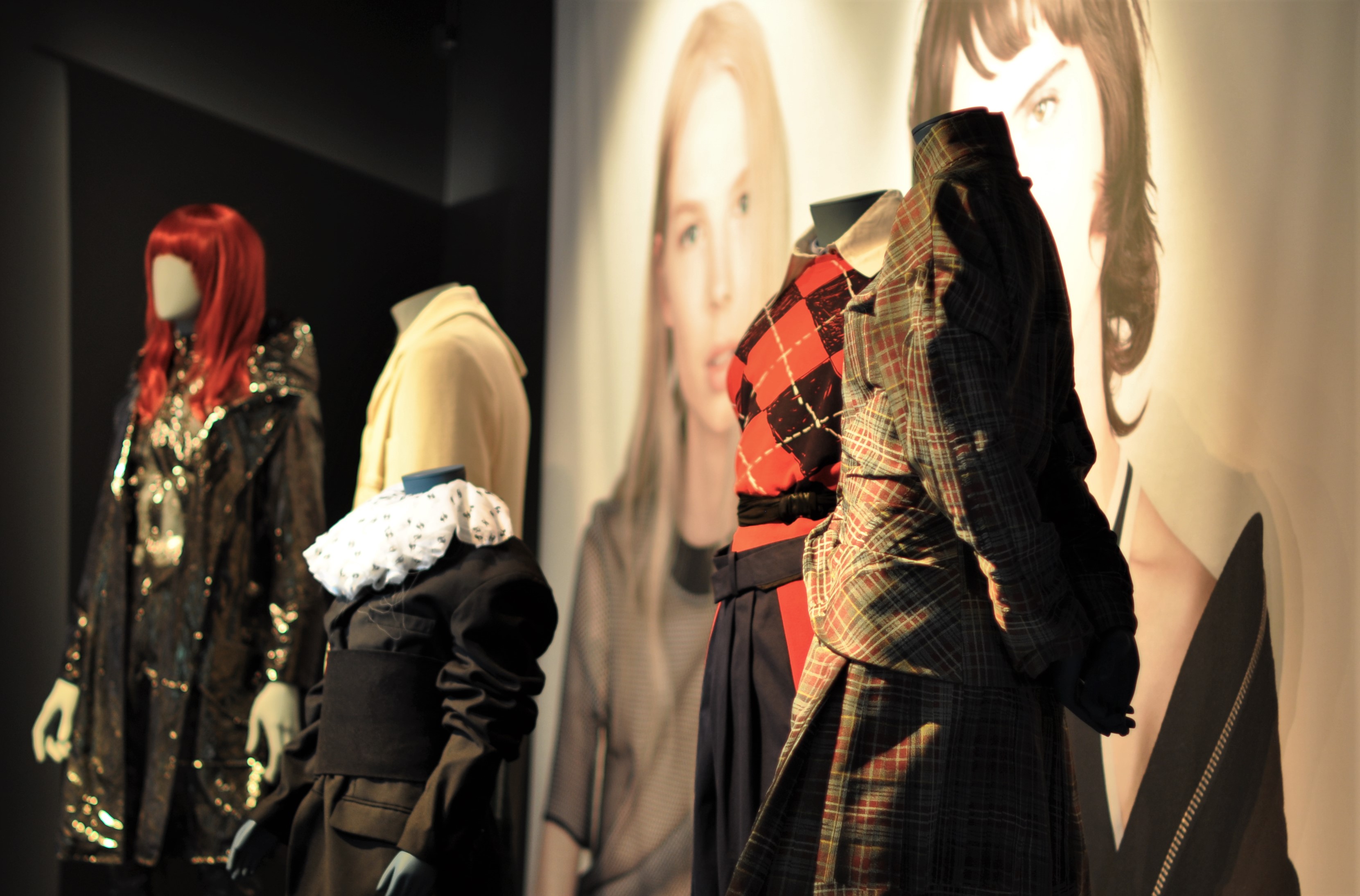 Five mannequins styled against exhibition backdrop.