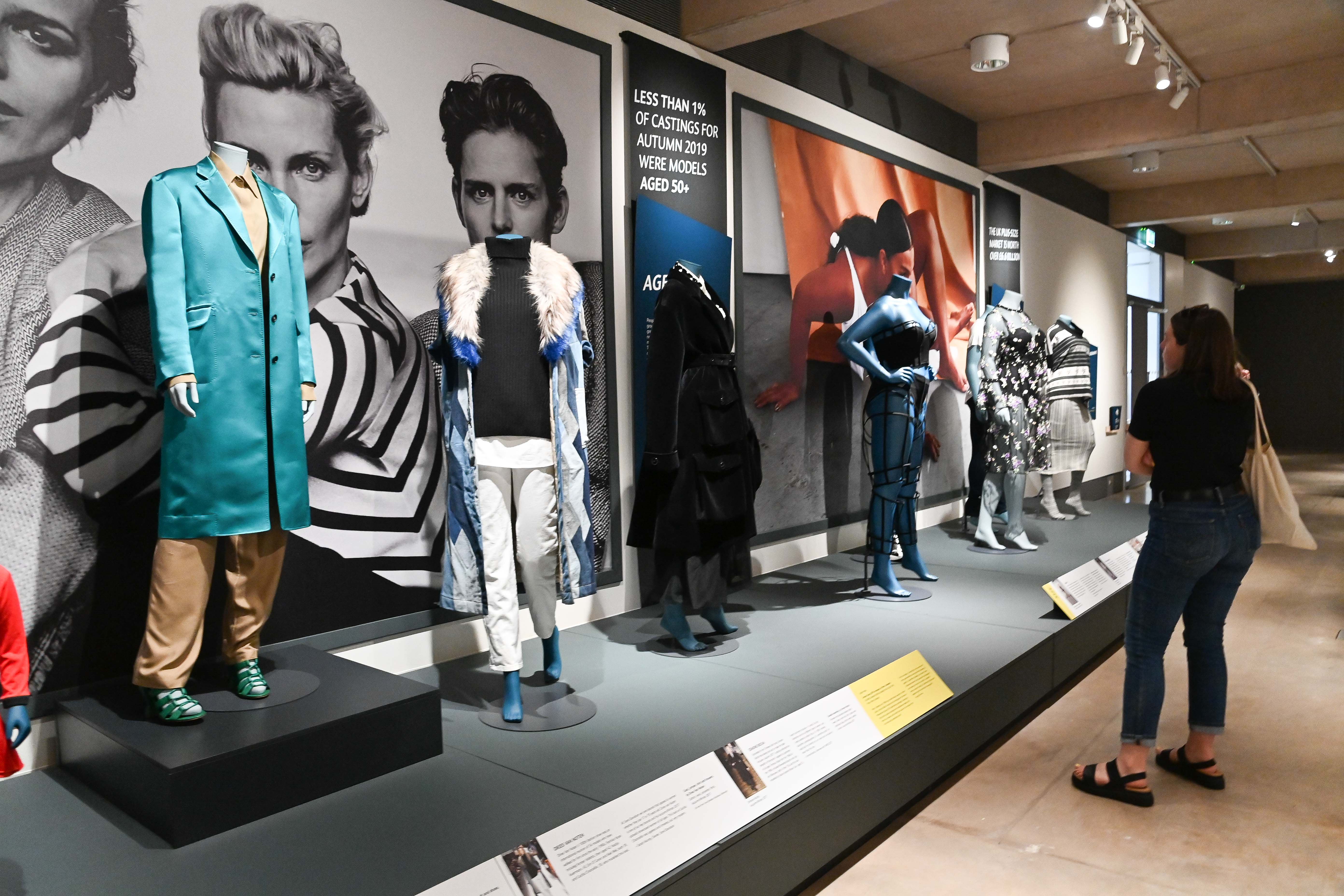 A visitor looks at seven mannequins within the exhibition.