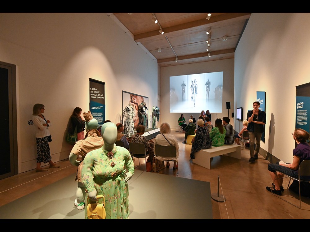 A group of people attend a talk within one of the gallery spaces during the exhibition.