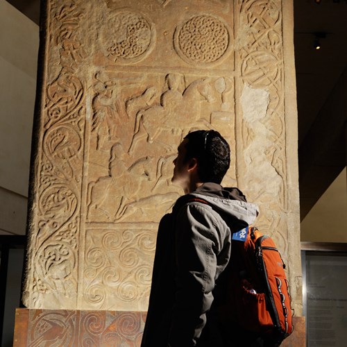 A visitor admires the Hilton of Cadboll stone, on display in Level -1 in the Early People gallery.