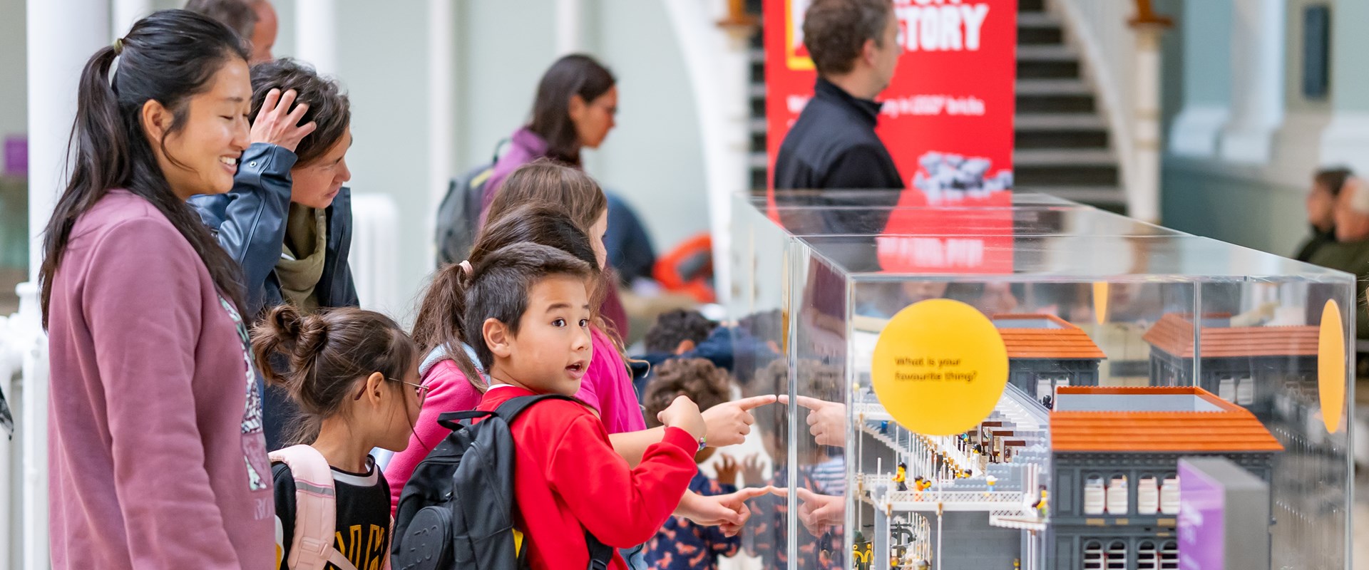 Young person points at a model of the museum made from Lego.