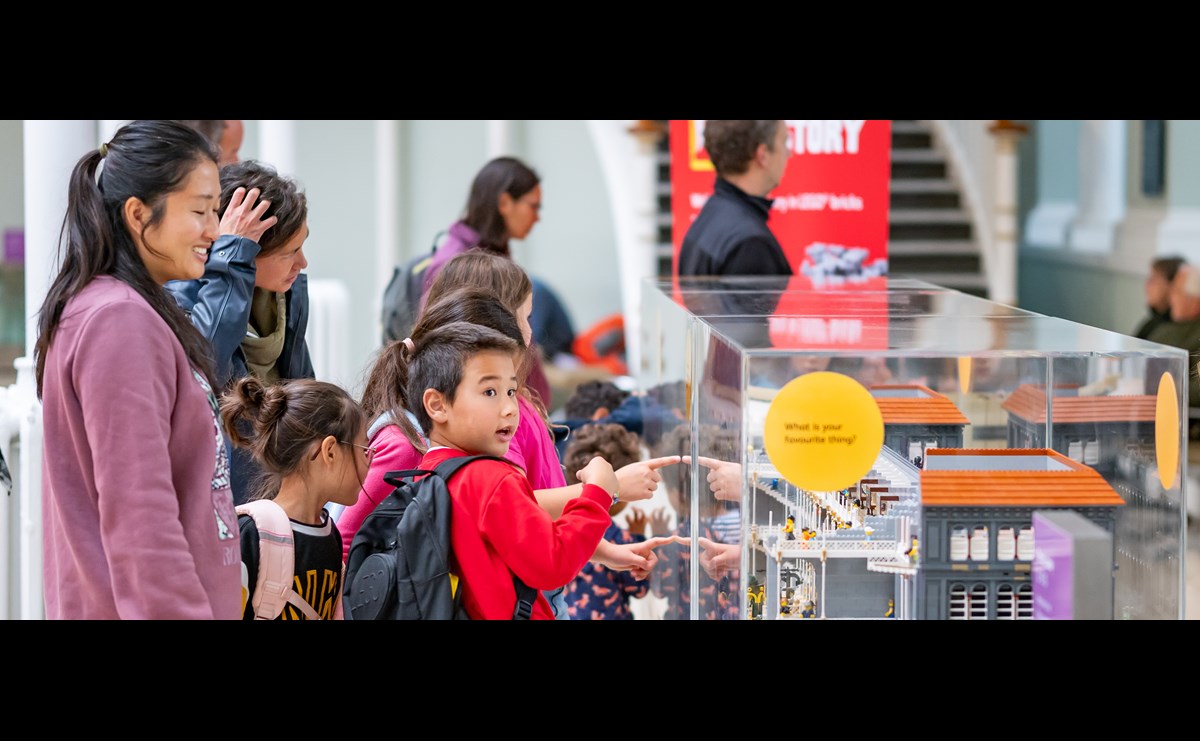 A child is pointing at a display case at the National Museum of Scotland, and looks excited.