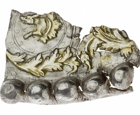 Silver fragment with jagged top edges and bulbous parts at the bottom with decorative gold leaves.