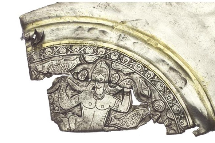 Silver fragment with gold lines showing a nude figure rising from the waves next to fish.