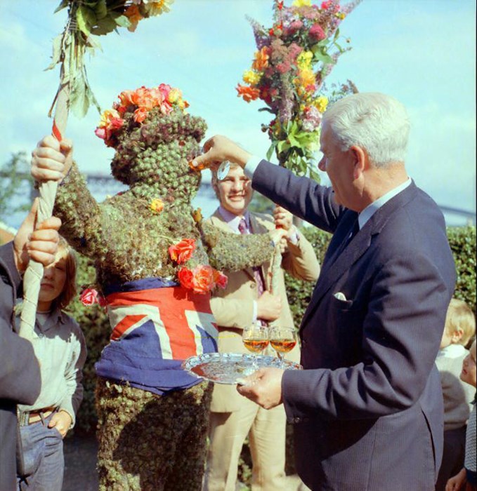 A man in a suit pretending to feed a statue made of flowers