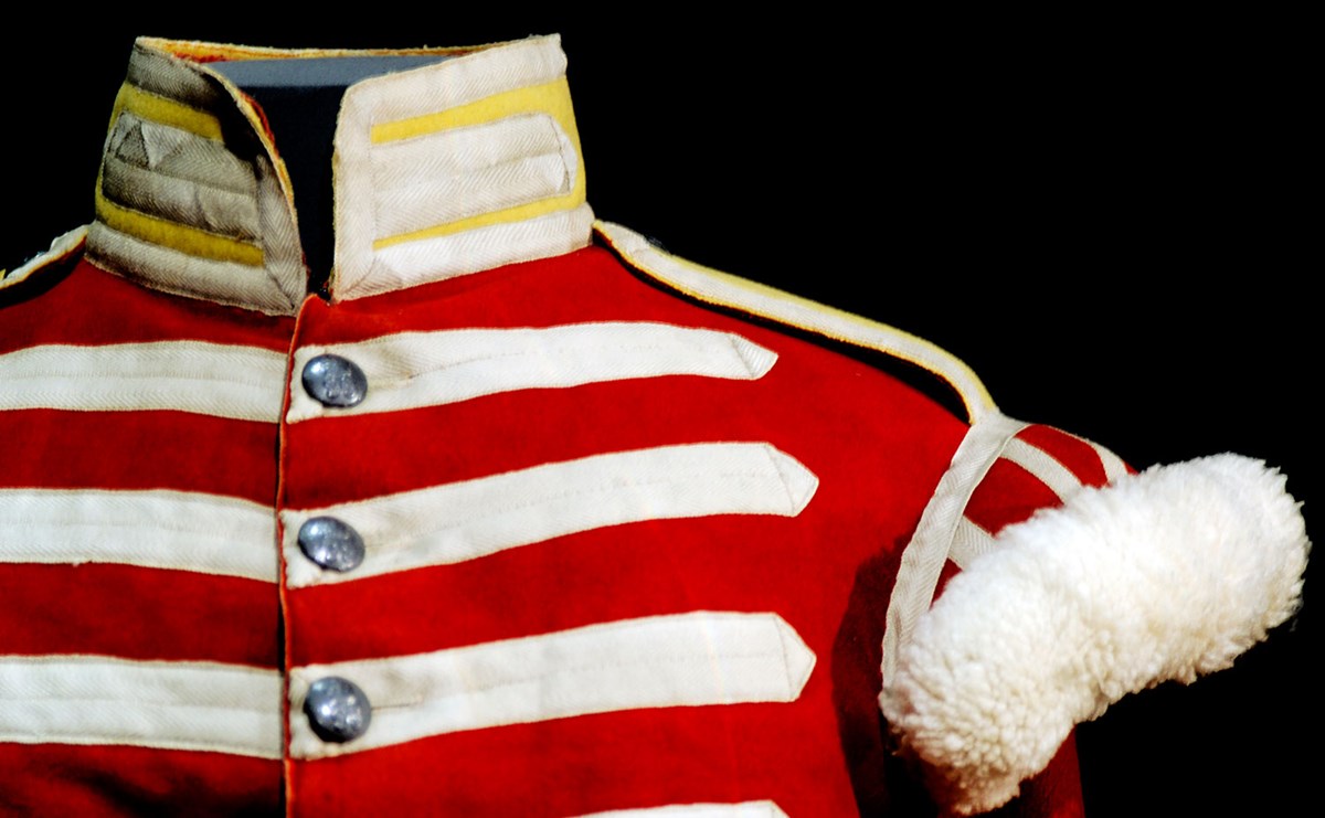 Shoulder of a red uniform with white stripes and sleeve embellishments. The collar is yellow and white.