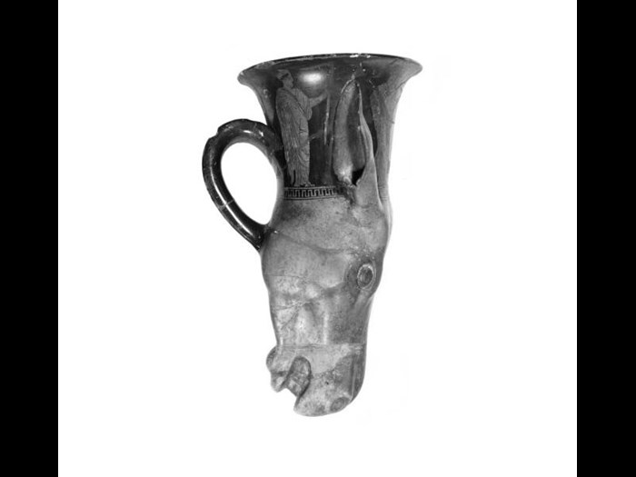 Rhyton of earthenware, in form of an ass's head with handle, covered with black and grey glazes and decorated with four standing figures, broken and repaired.