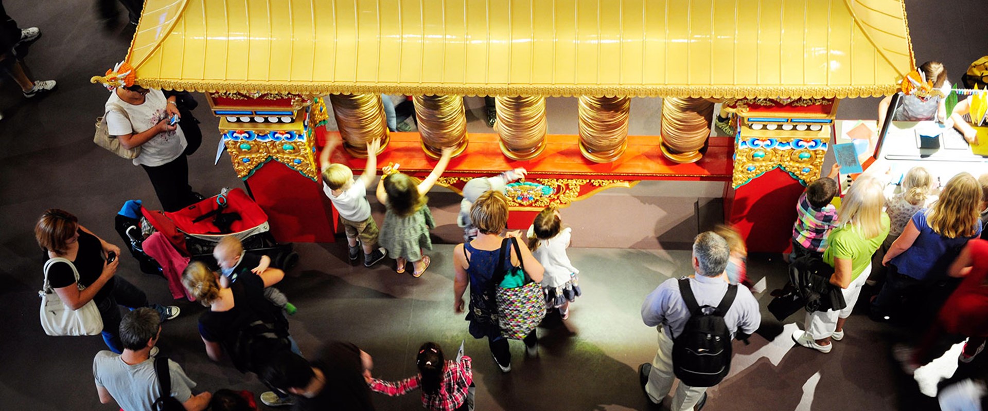 Visitors interact with the Tibetan prayer wheel, on display on Level 1 in the Living Lands gallery
