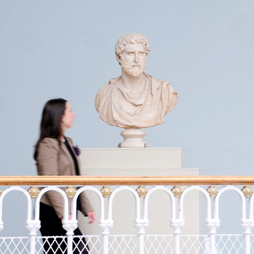 A visitor looking at a sculpture bust.