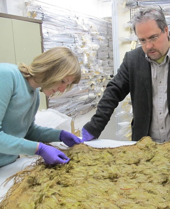 Eve Haddow and Mark Hall examining a unique Māori feather cloak covered in kākāpō (night parrot) feathers.