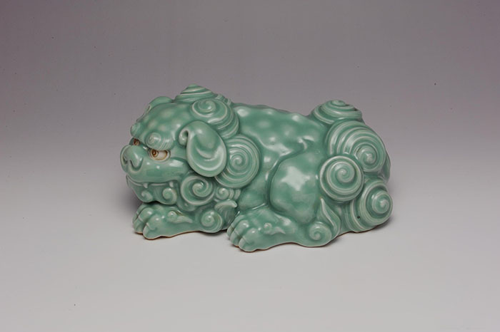 Sculpture of recumbent lion-dog (shishi) with celadon glaze, by Makuzu Kozan I, 1900 - 1910.