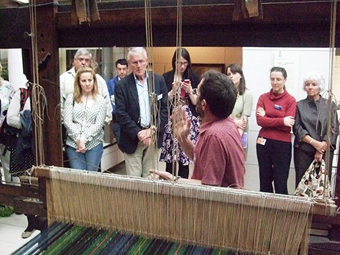 A man demonstrates a loom to a group of visitors
