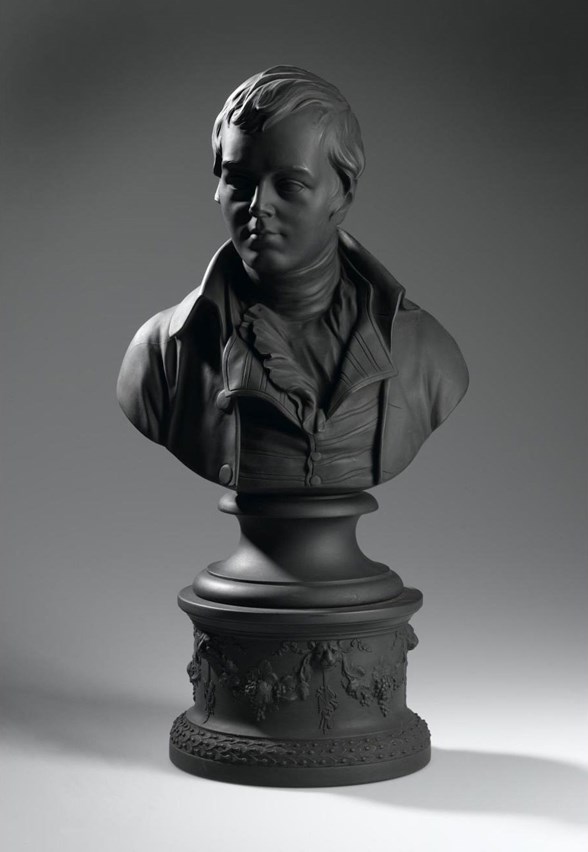 Black bust, very smooth and lifelike, of Robert Burns looking to the side atop a decorated column.