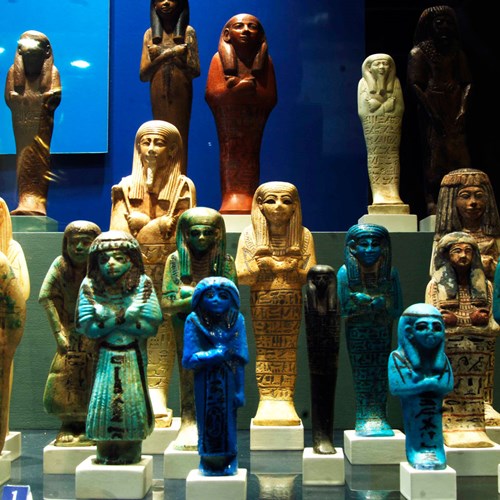 A variety of small Ancient Egyptian statues of humans with arms crossed.