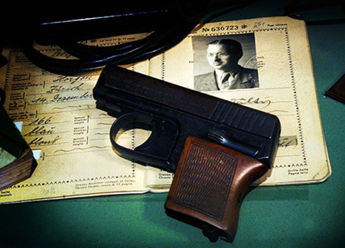 A pistol lying on a table on top of an identification card.
