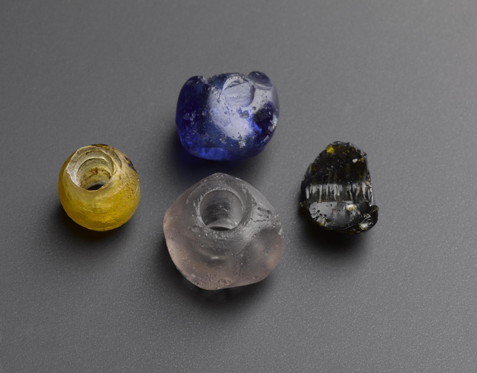 Image of Three glass beads, one bead of faceted clear glass, one bead of yellow glass and a half black glass bead, from Samhnan Insir, Isle of Rhum, Inverness-shire, 18th - 19th century © National Museums Scotland
