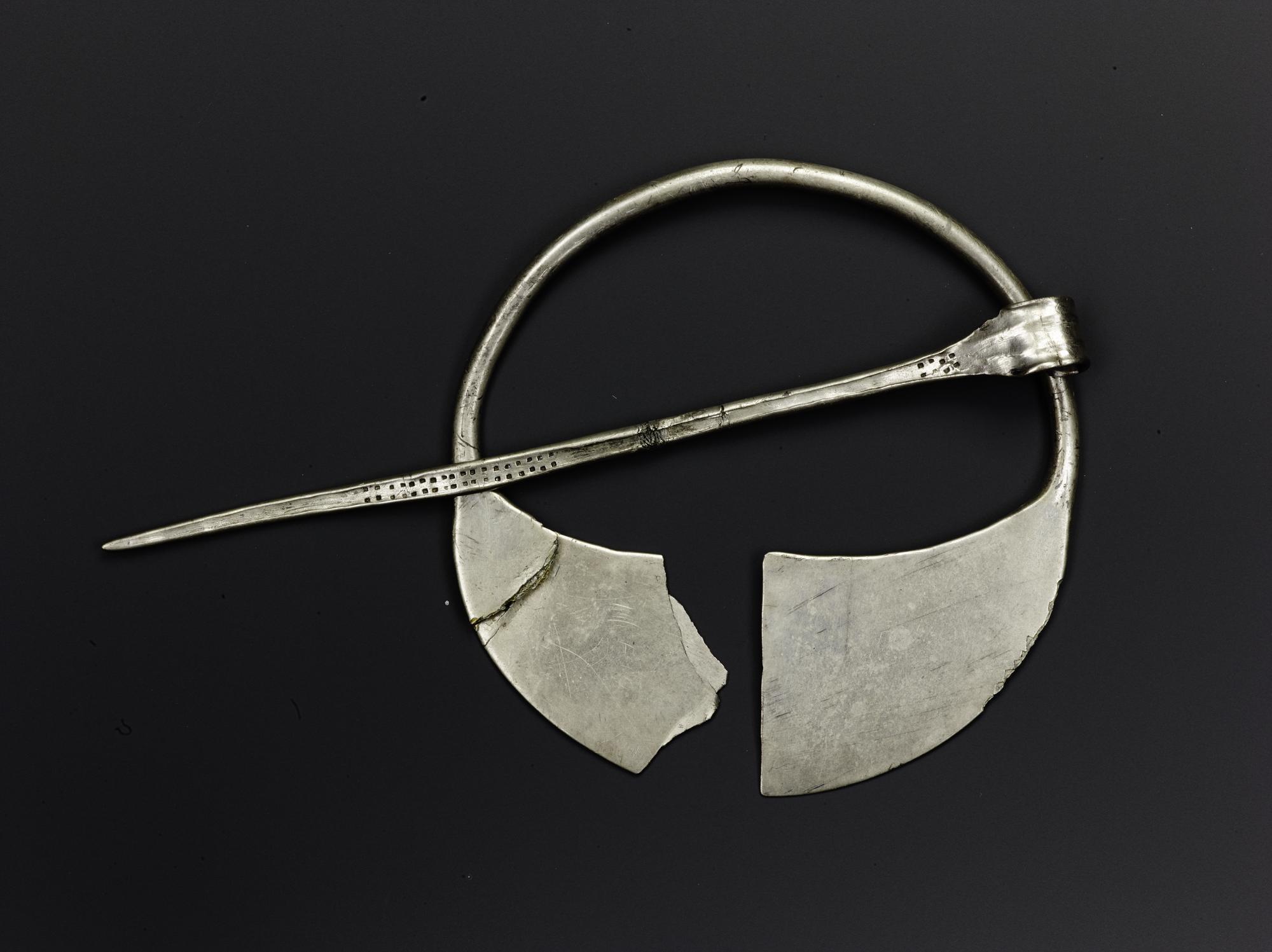 Image of Silver brooch formed of a round ring with expanded and flattened end, ornamented with two rows of dots on pin, from Tummel Bridge © National Museums Scotland