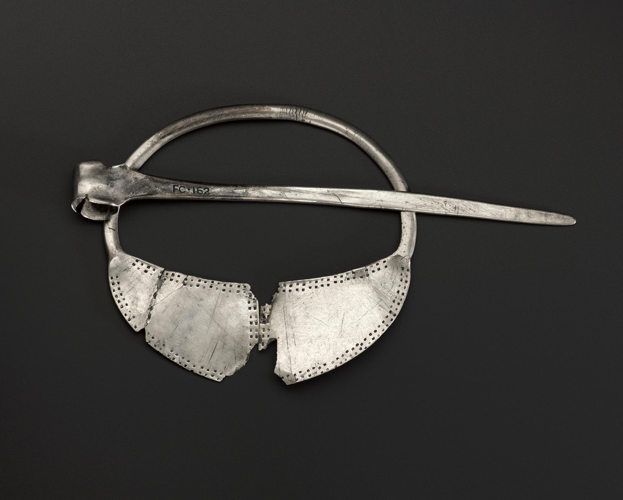 Image of Silver brooch formed of a round ring with expanded and flattened end, ornamented with two rows of dots round the edges, from Tummel Bridge © National Museums Scotland