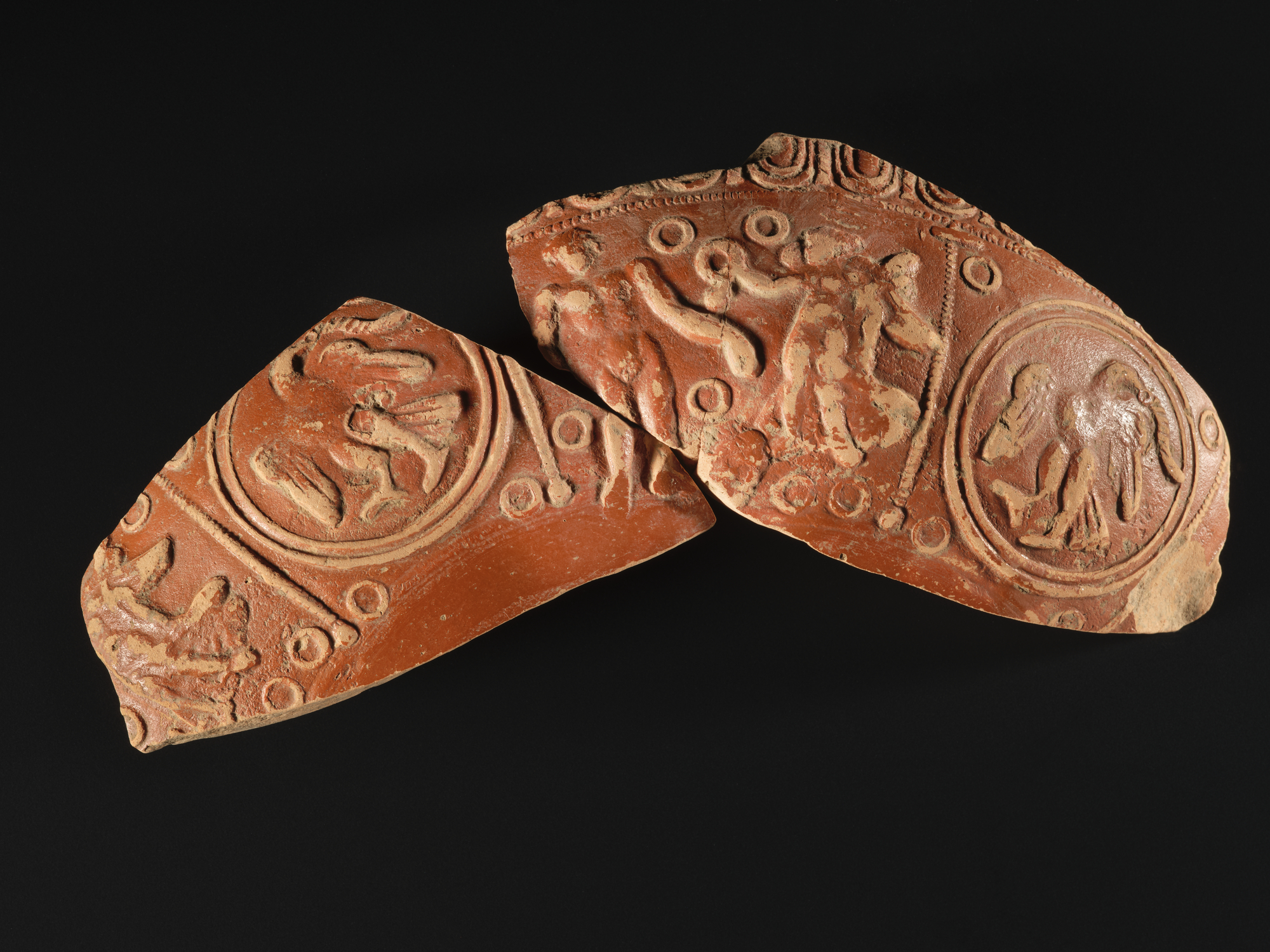 Image of Fragment of a bowl of samian ware, ornamented with an eagle with a snake in its beak and Victory offering a wreath to a nude figure, from the Roman site at Newstead © National Museums Scotland