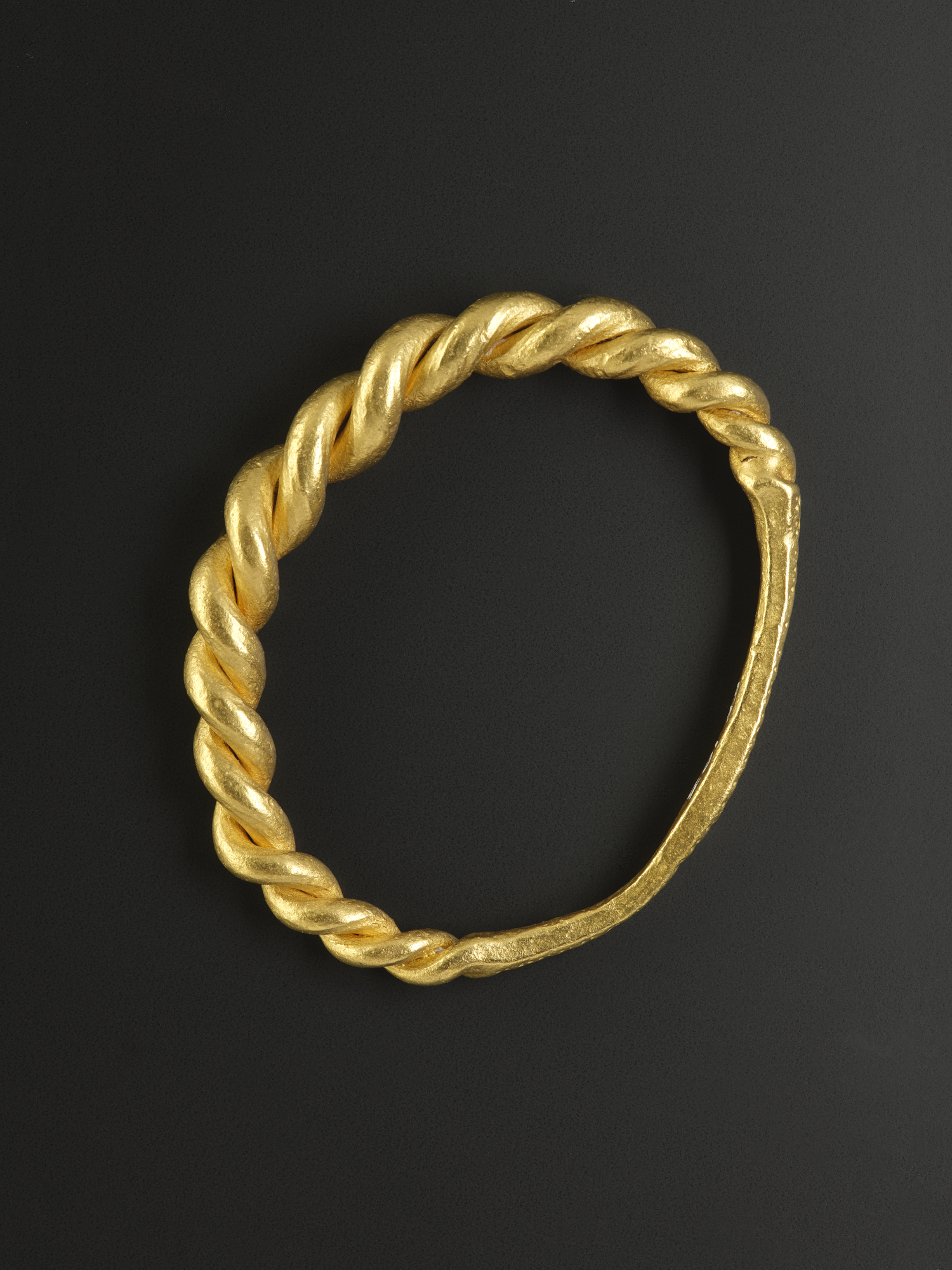 Image of Gold arm-ring consisting of two rods twisted together merging into an elongated plate and decorated with ring-stamps and punched dots, Viking, found in the Sound of Jura, Argyll, 10th century © National Museums Scotland