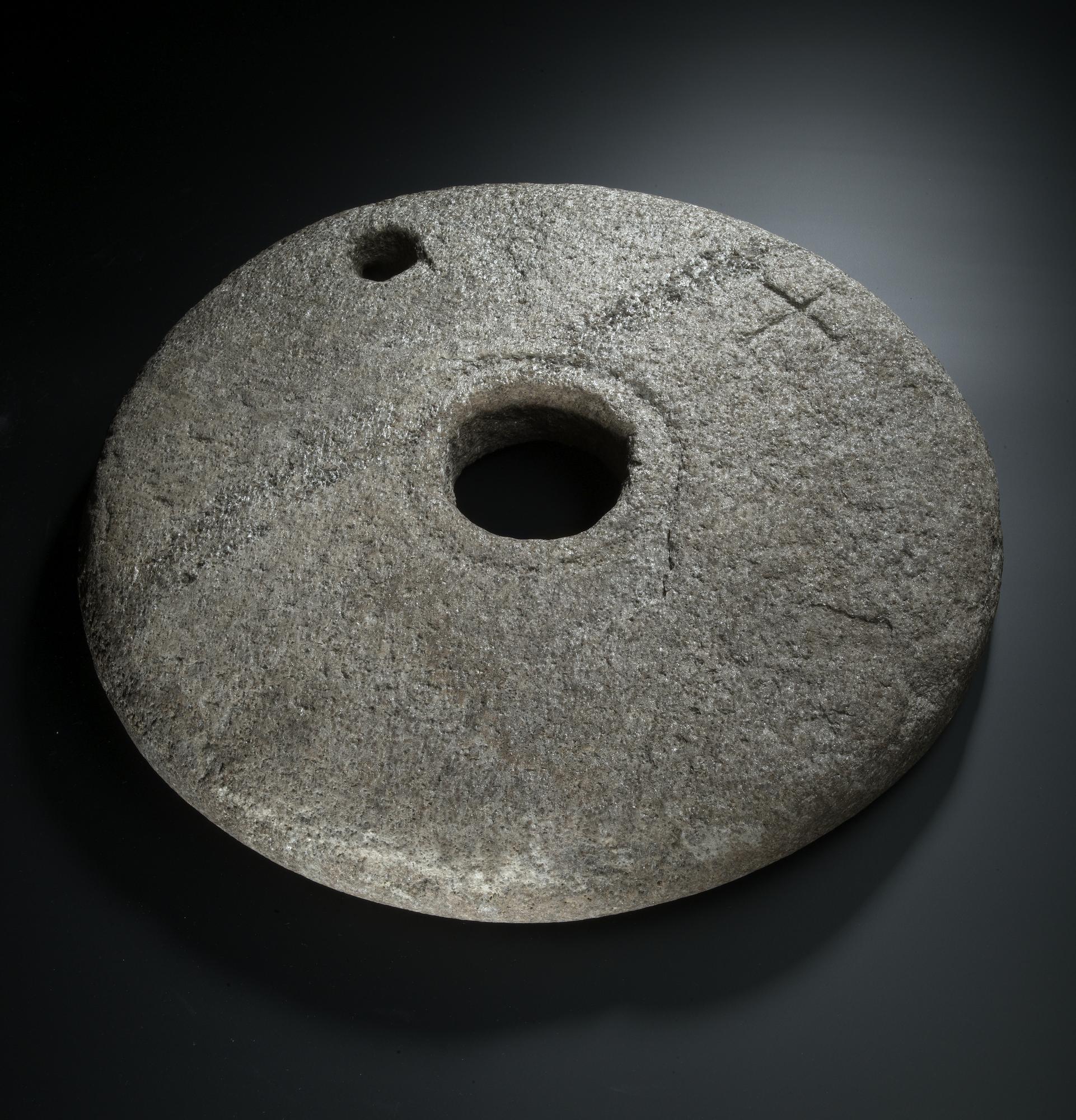 Image of Quernstone of micaceous stone with a cross incised near the edge, from Dunadd, 580 - 800 AD © National Museums Scotland