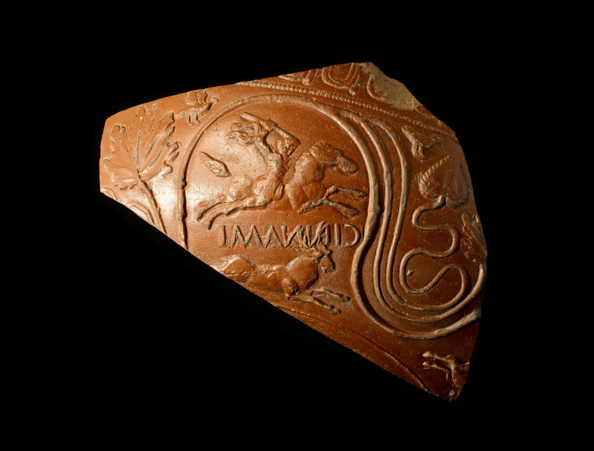 Image of Fragment of a bowl of Samian ware decorated with a man hunting a stag, stamped to indicate manufacturer, from the Roman site at Newstead, 140 - 180 AD © National Museums Scotland